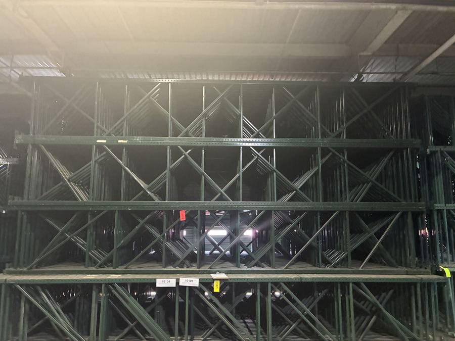 Green Ridg-U-Rak slotted pallet rack uprights stacked in the AMH West Memphis warehouse