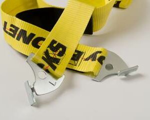 The image shows a pair of Adrian safety straps, featuring bright yellow webbing with black text and logos printed on them. Each strap ends with a sturdy metal hook designed for secure attachment. The hooks are silver-colored and have a unique shape that ensures they can be easily and firmly connected to the corresponding rack or support structure. The straps are made of durable material, ensuring they can withstand significant tension and provide reliable support for securing items in place. The overall design highlights both safety and durability, making them suitable for use in various industrial and warehouse applications.